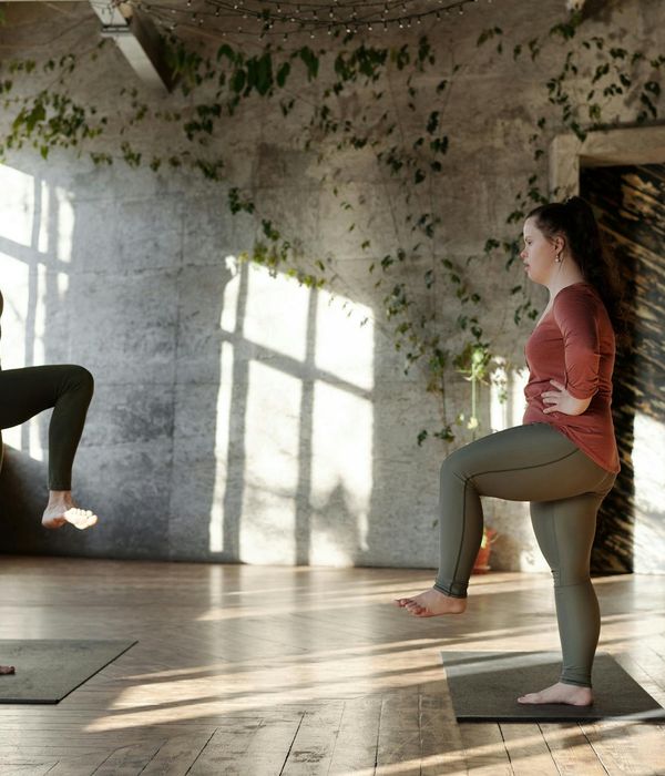 Woman practicing a balancing cardio pose in a light-filled room.